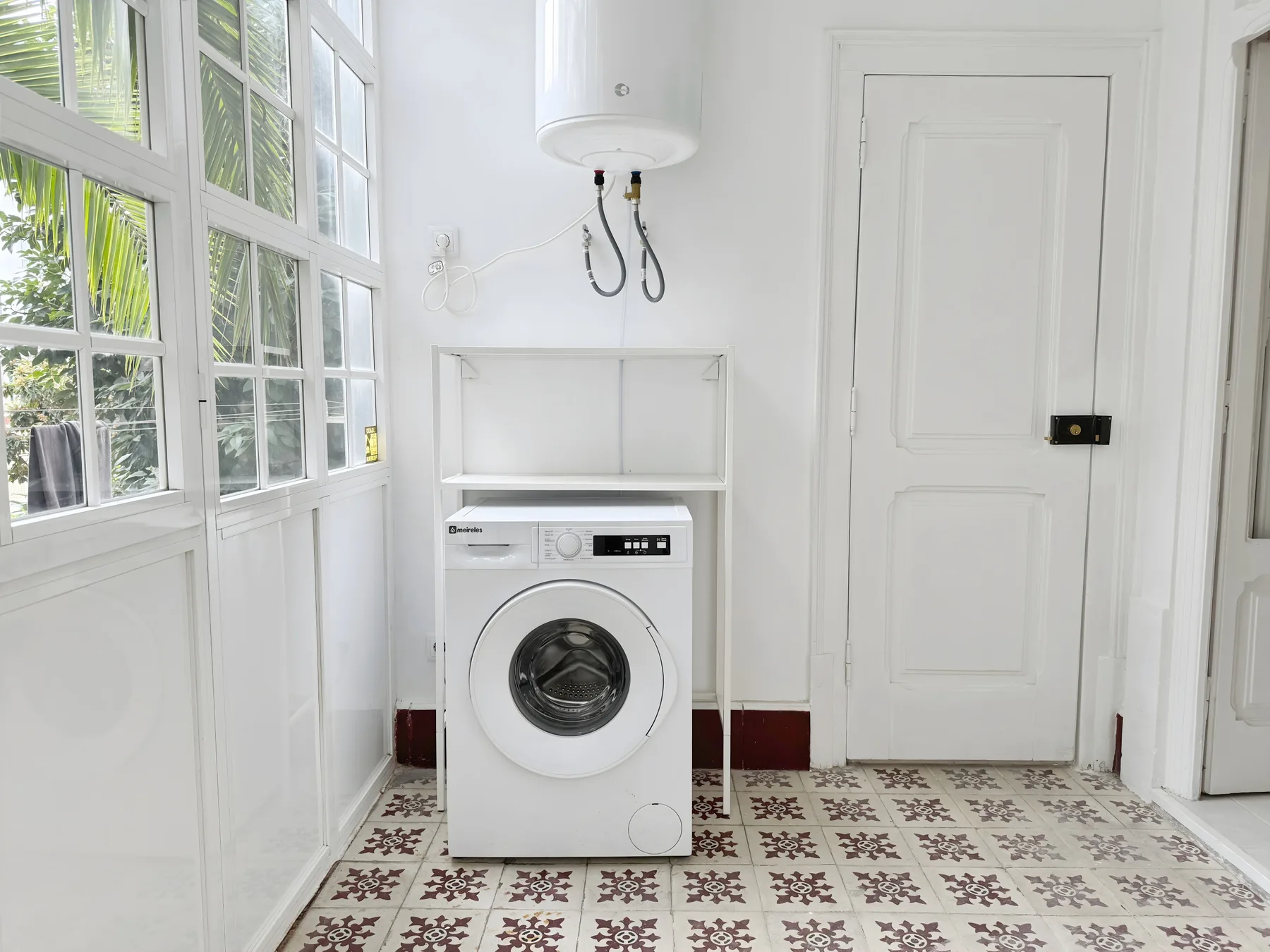 A bright laundry area with a front-loading washing machine beneath a wall-mounted water heater.