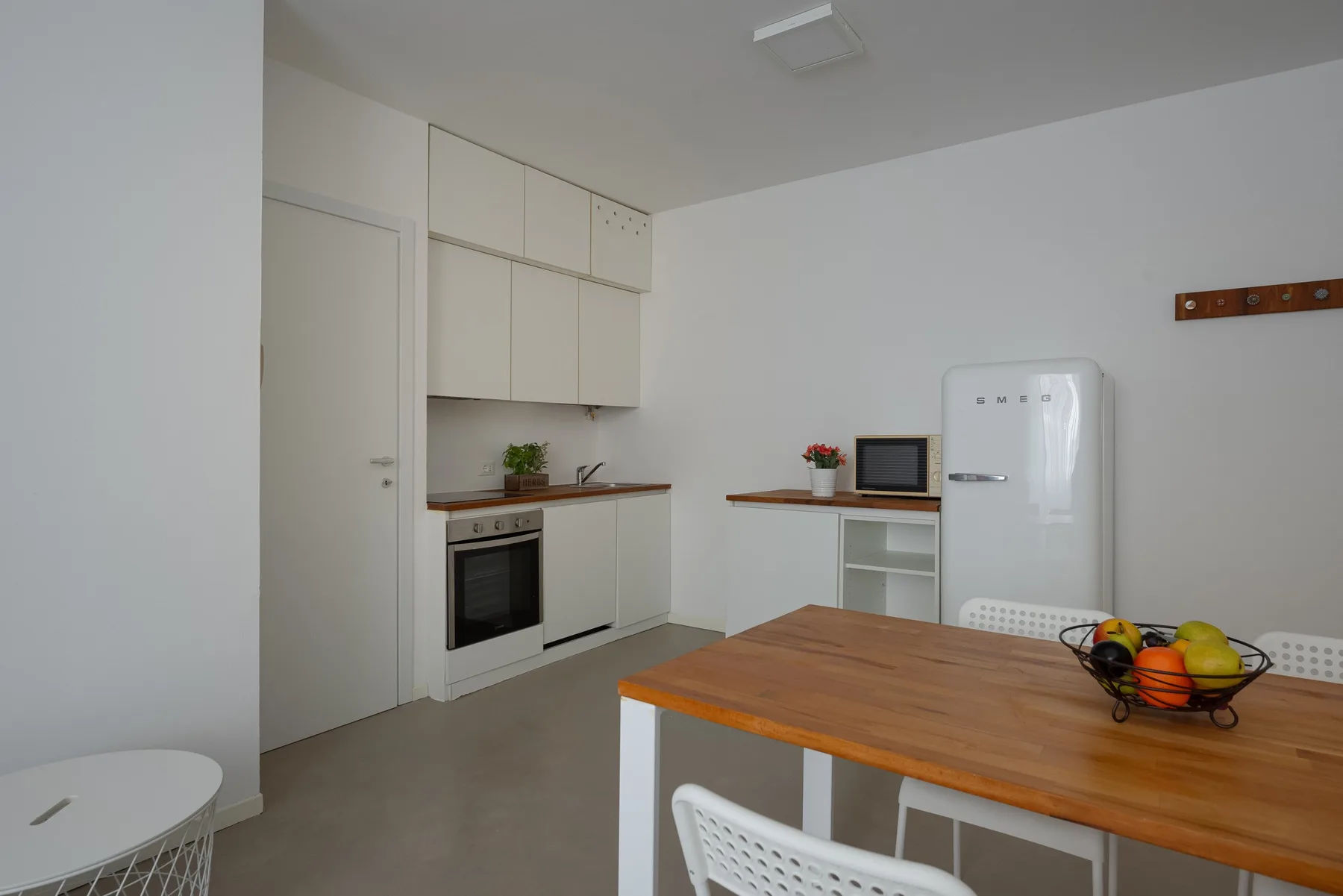 A bright kitchen and dining area with white cabinets and a wooden table.