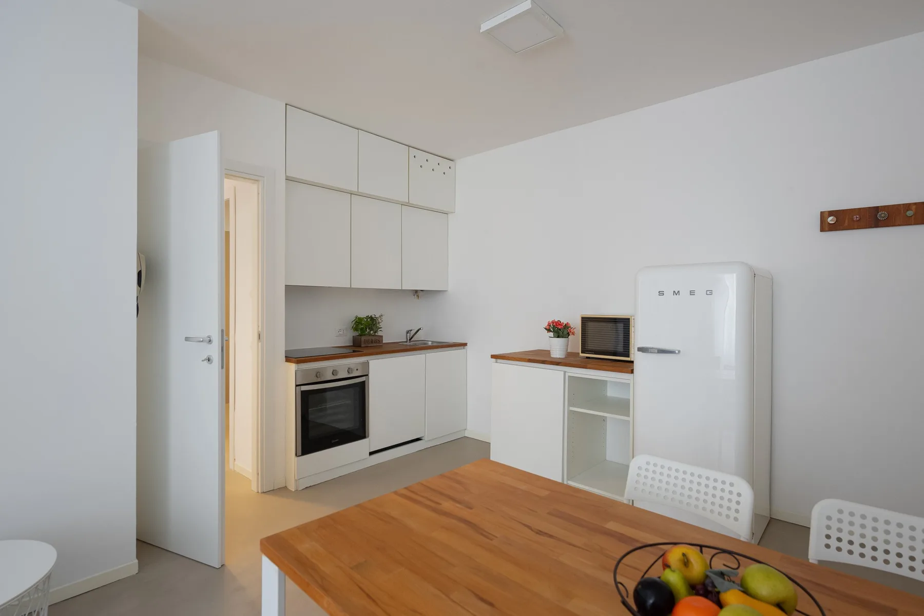 A bright kitchen with white cabinets and a wooden table.