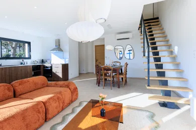 A bright open-plan living and dining area with a kitchen and staircase.