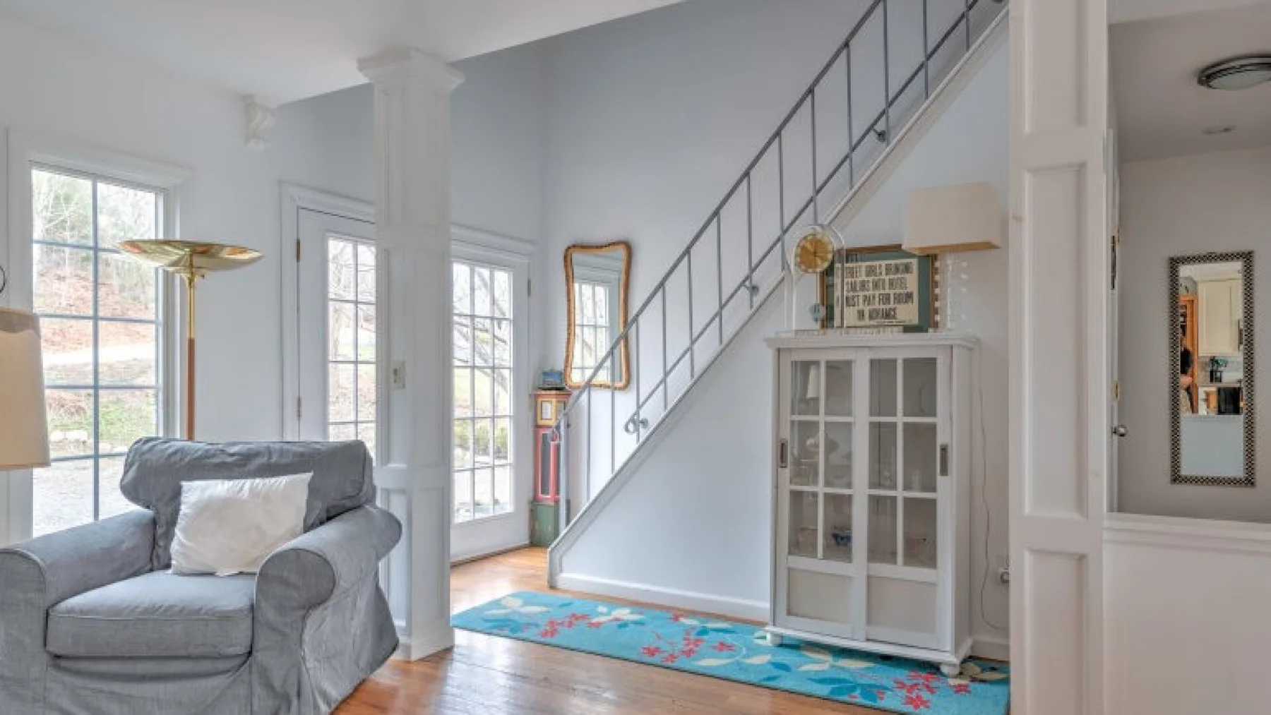 Una sala luminosa con asientos junto a una escalera y grandes ventanas.