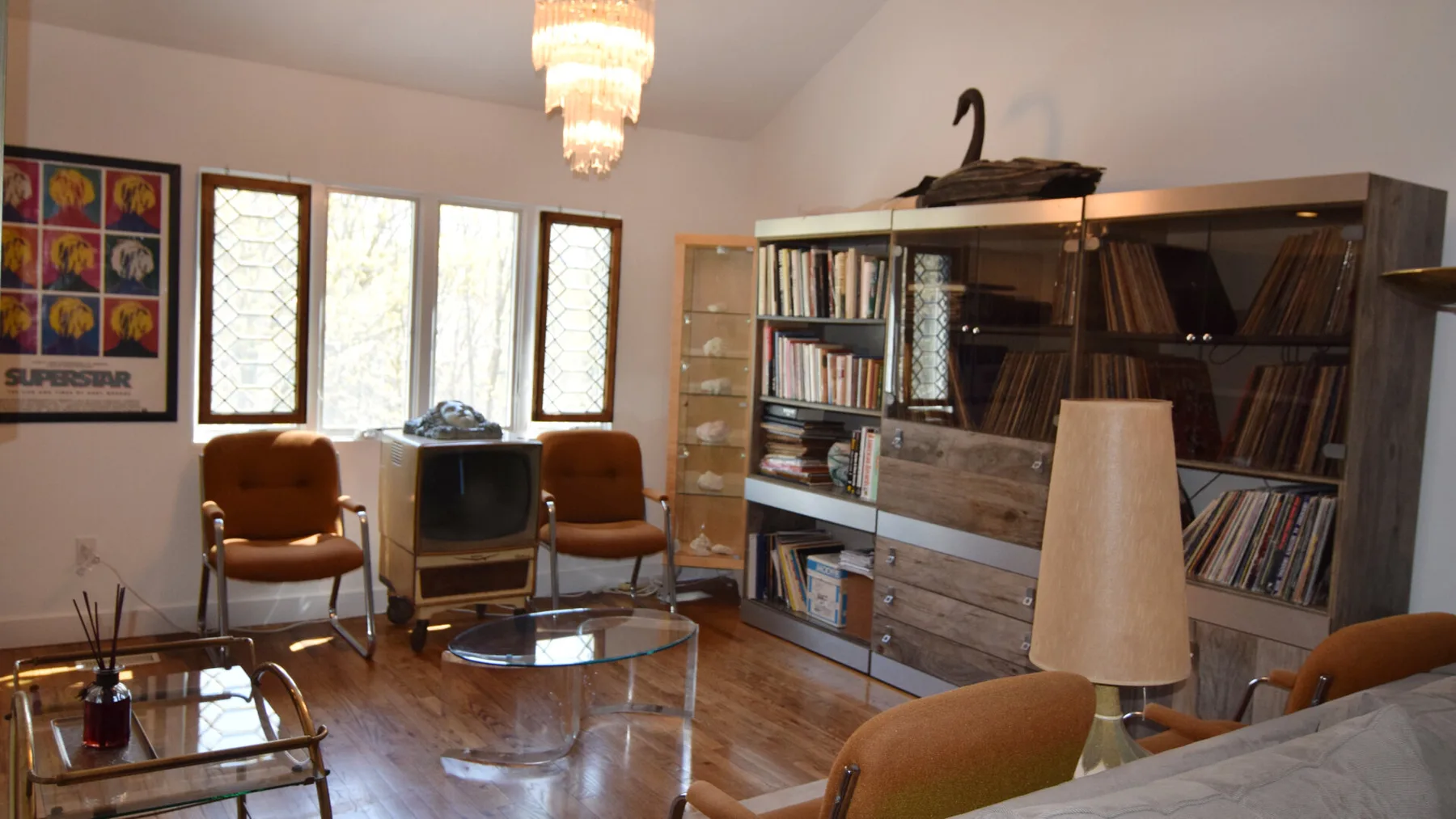 Una sala de estar con asientos, un televisor y una gran librería.