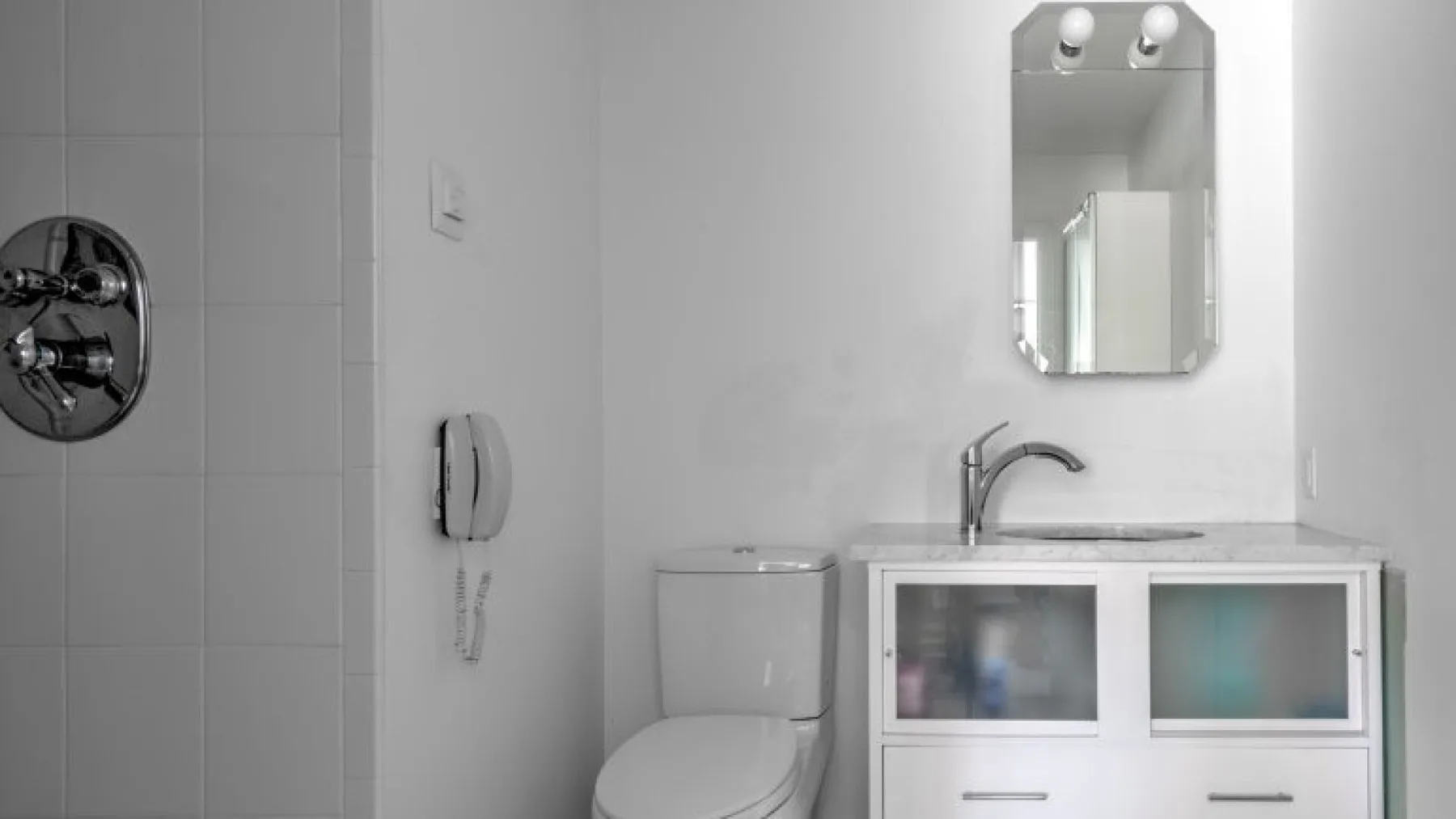 Un baño alicatado con inodoro, lavabo y espejo de pared.