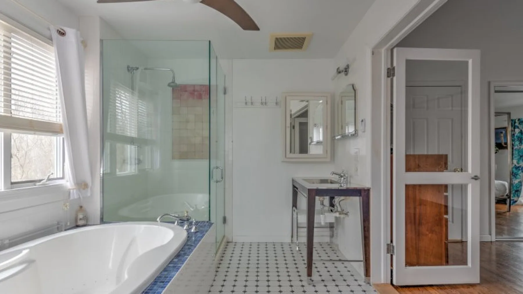Un baño luminoso con bañera, ducha de vidrio y tocador.