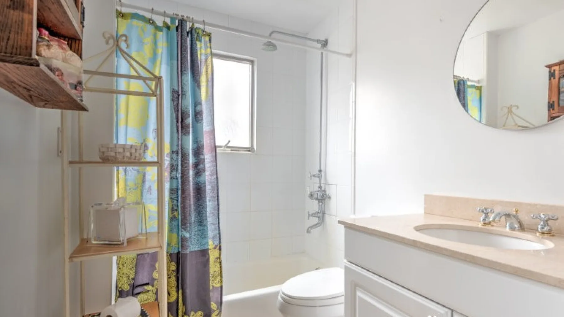 Un baño con lavabo, inodoro y ducha detrás de una cortina colorida.