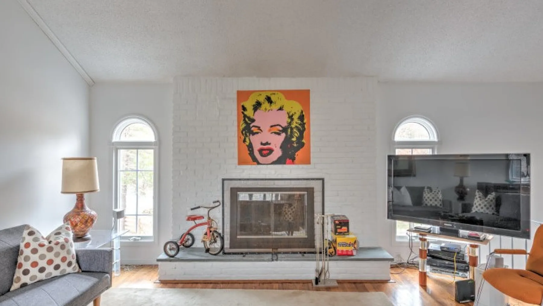 Una sala de estar con chimenea, asientos y arte colorido en la pared.