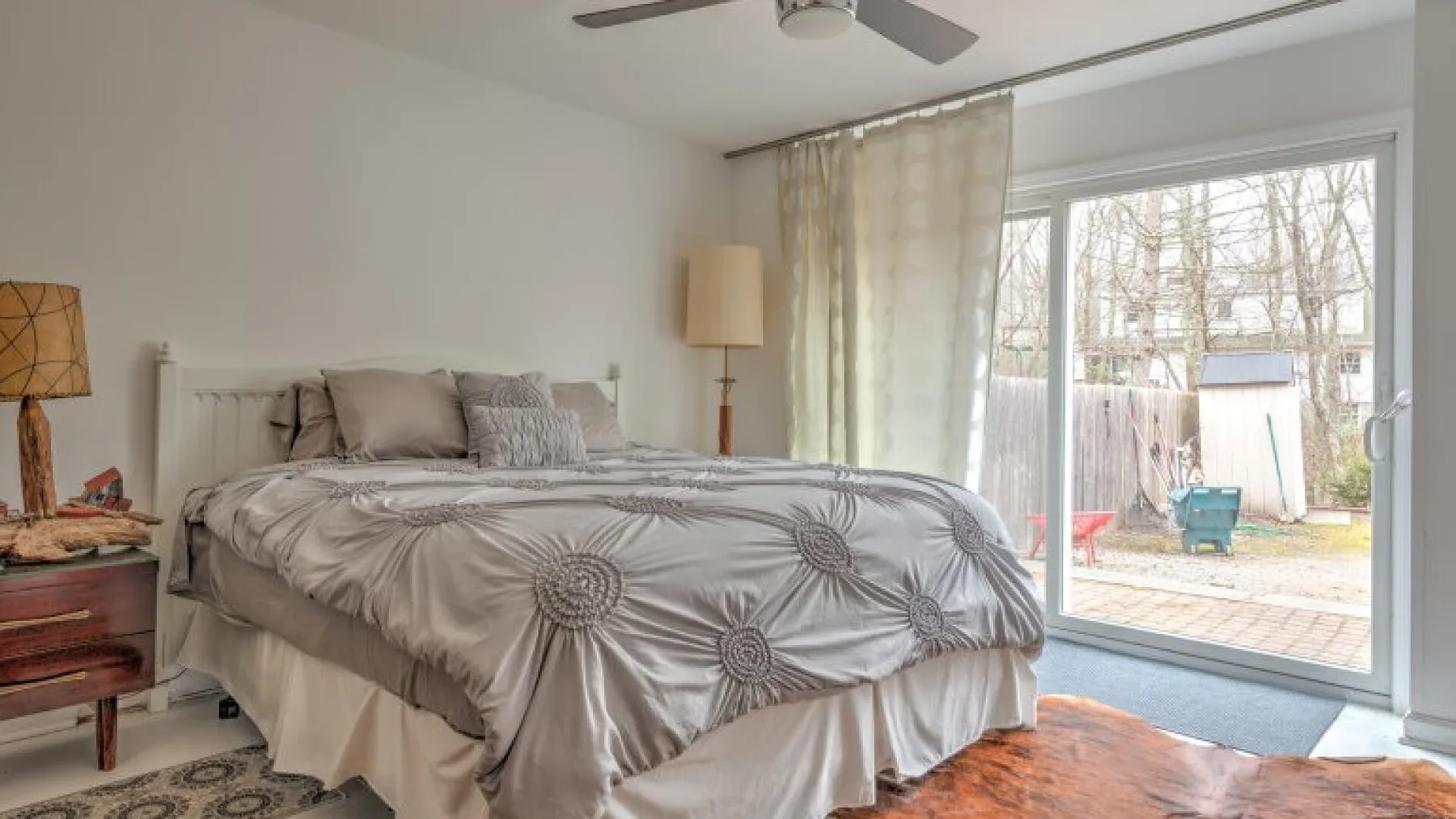 Un dormitorio con una cama junto a una gran puerta de vidrio que da a un patio.