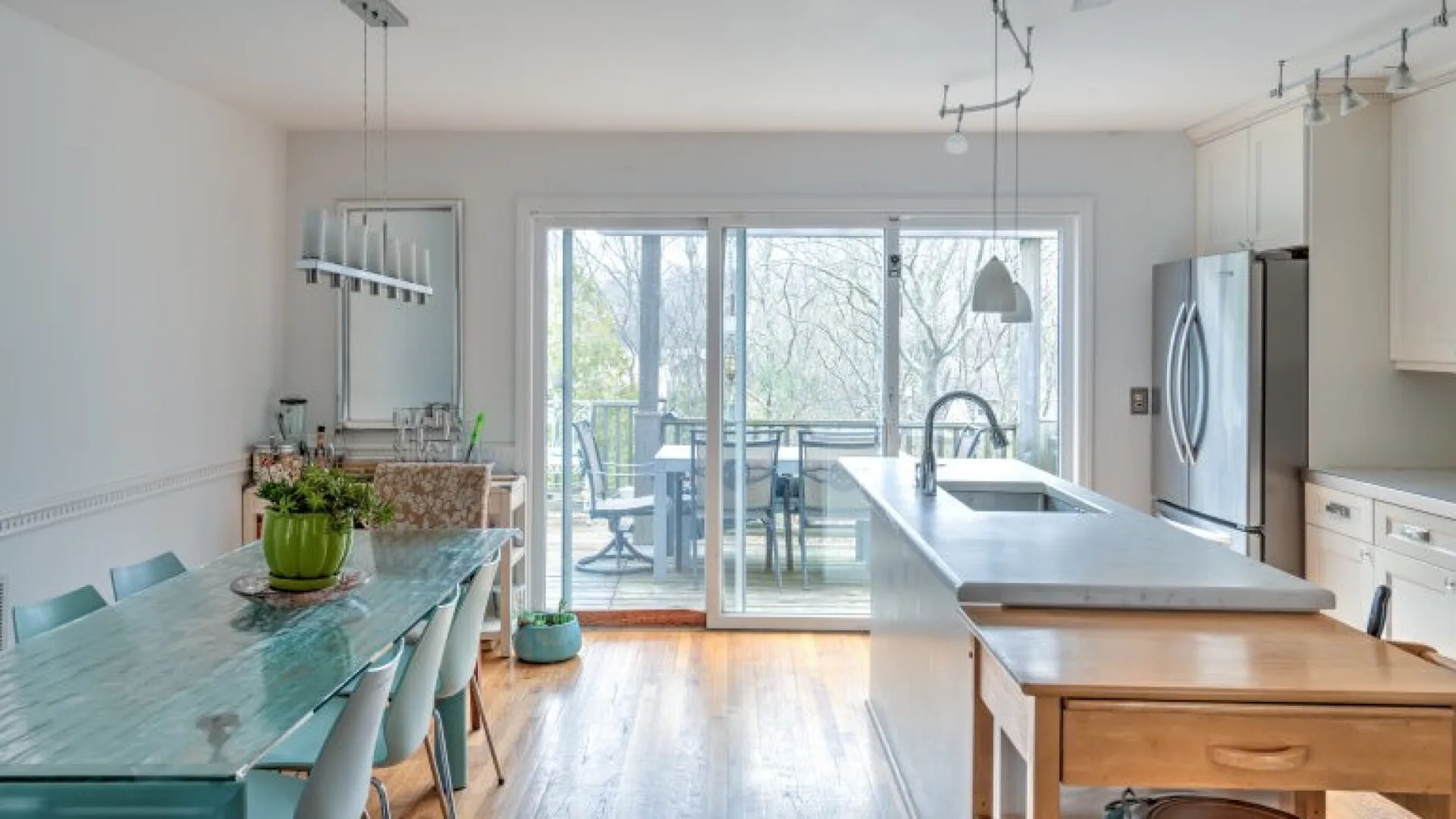 Una cocina y comedor luminosos con una isla larga y puertas de vidrio hacia un patio.