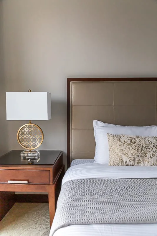 A bedroom with a neatly made bed and a bedside table.