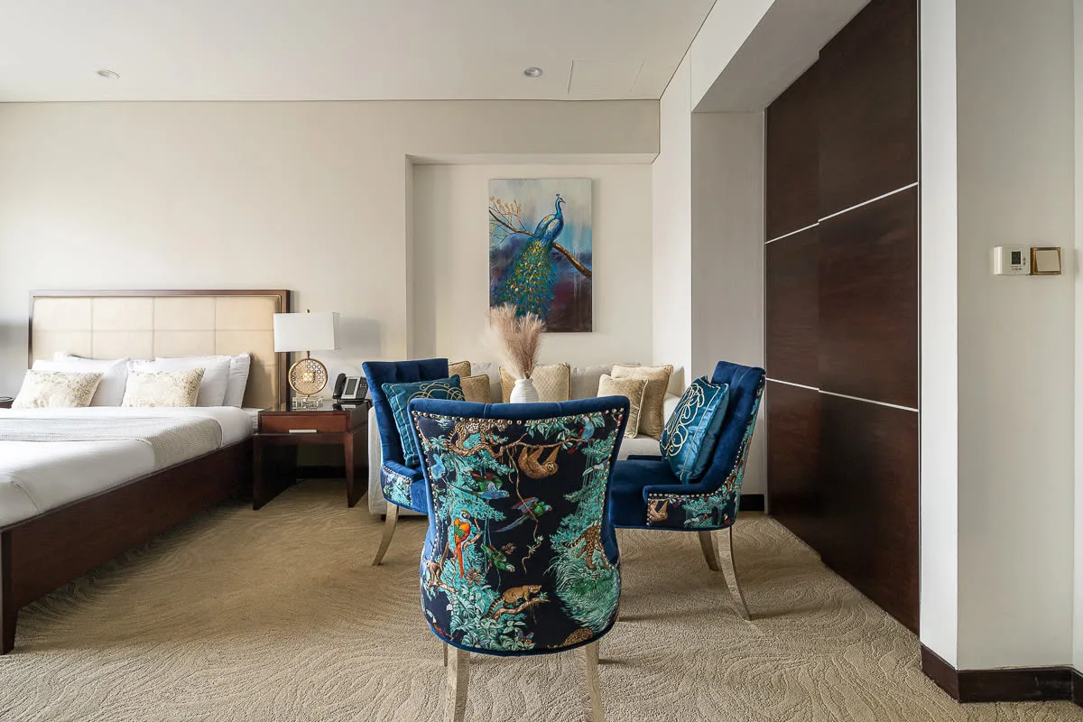 A bedroom with a bed and a small seating area.
