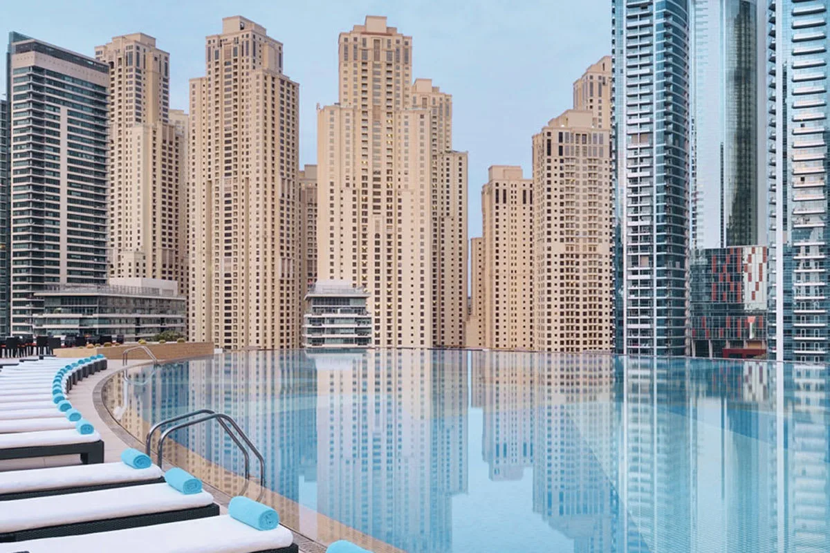 A swimming pool reflects the surrounding high-rise buildings.