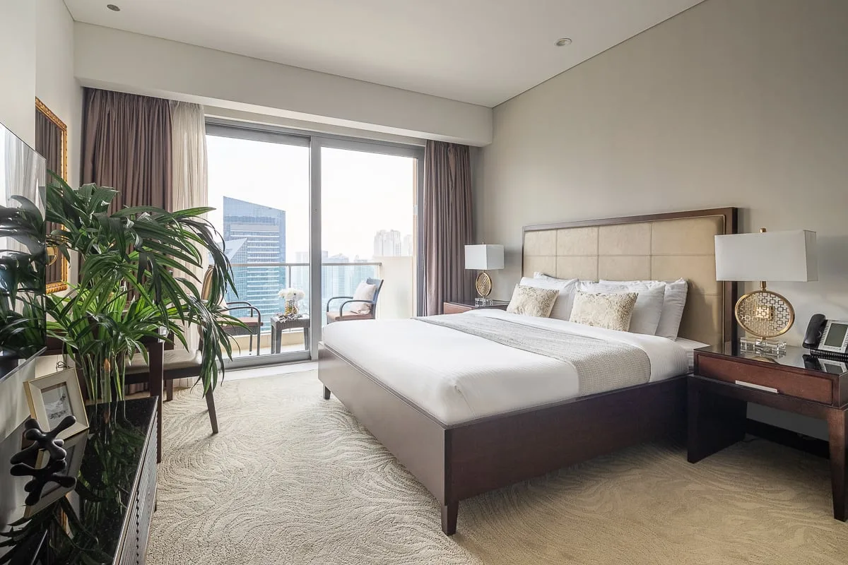 A bright bedroom with a large bed and sliding glass doors opening onto a balcony.