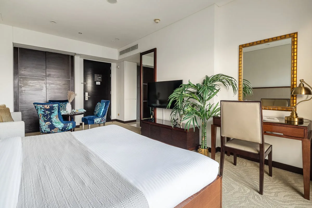A bedroom with a bed, seating area, television, and desk.