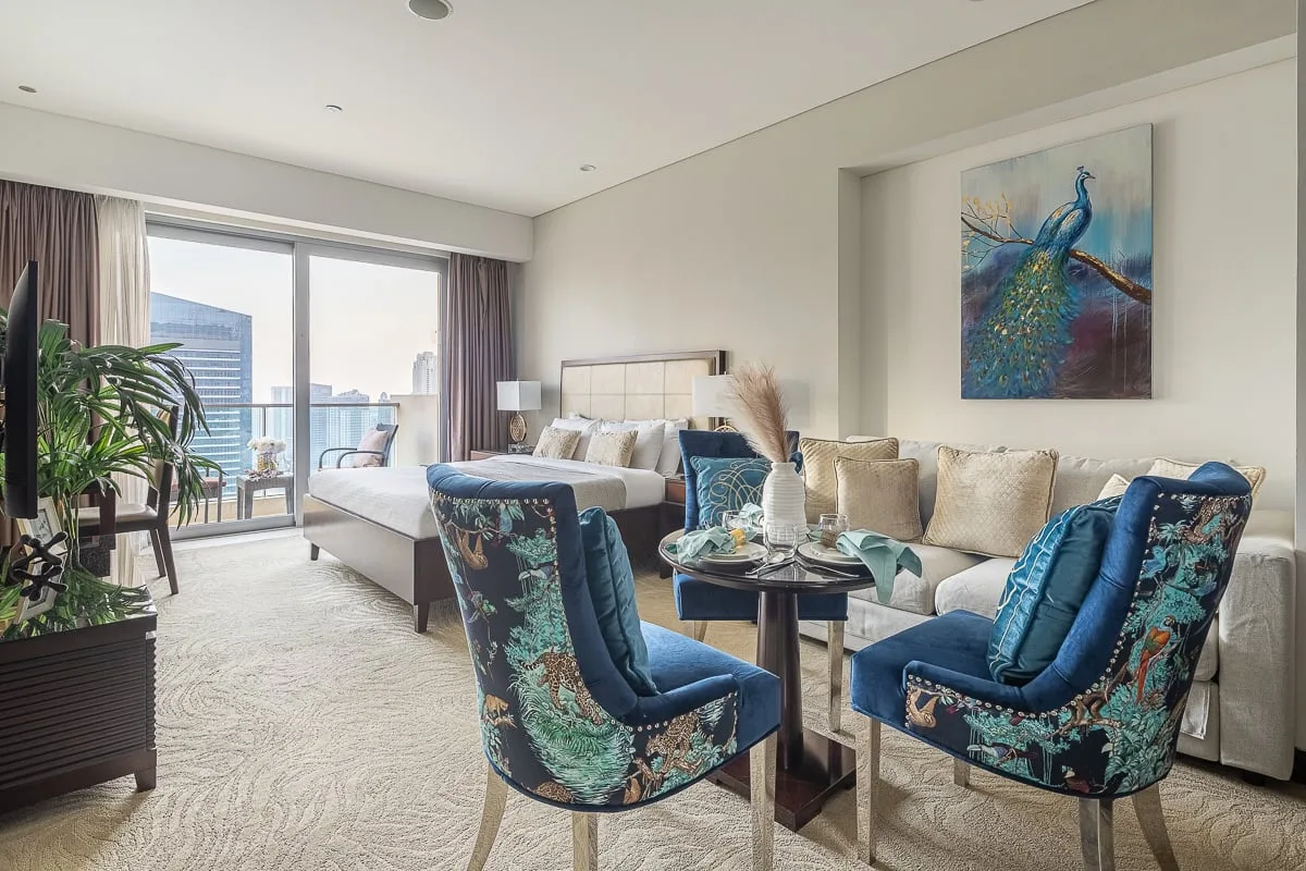 A bright living room with cushioned seating, a coffee table, and large windows.
