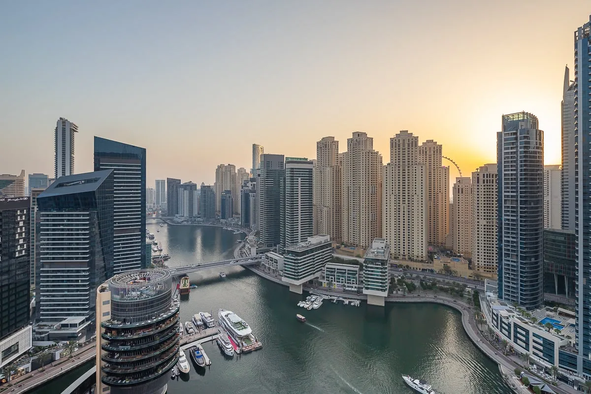 City skyline and waterfront canal at sunset, with high-rise buildings lining the water.
