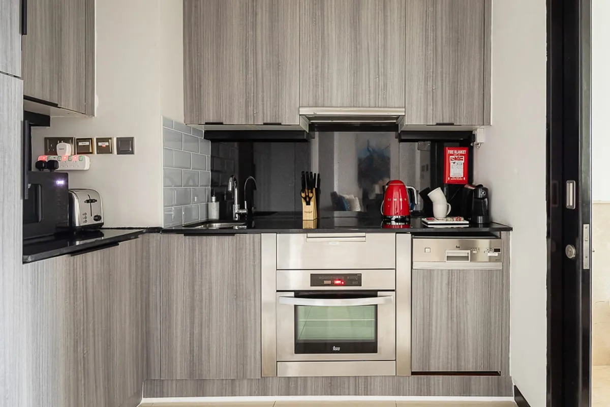 A modern kitchen with gray cabinetry, a countertop, and built-in appliances.