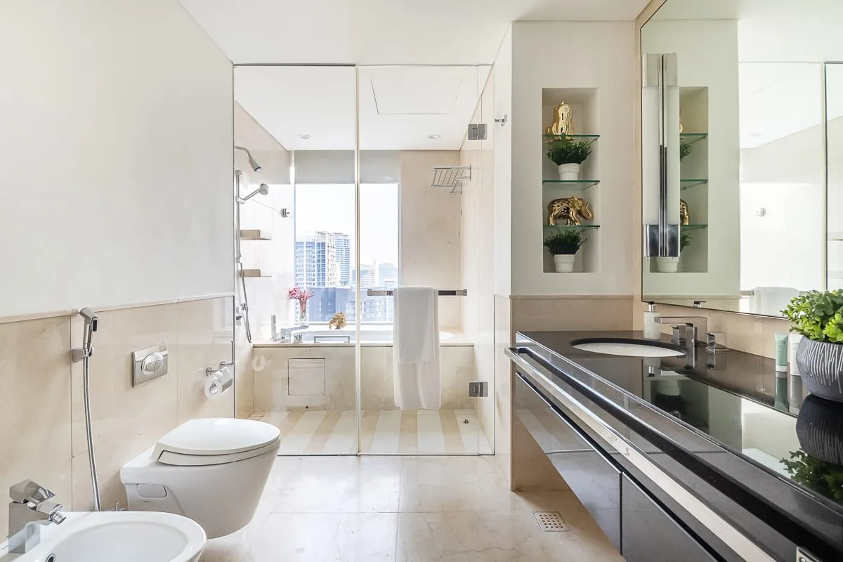 A bright bathroom with a glass shower and a long vanity.