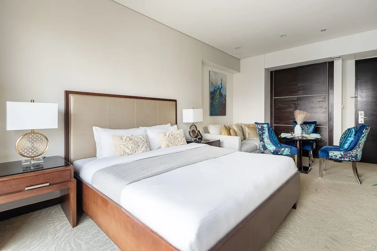 A bedroom with a large bed and a small seating area by the window.