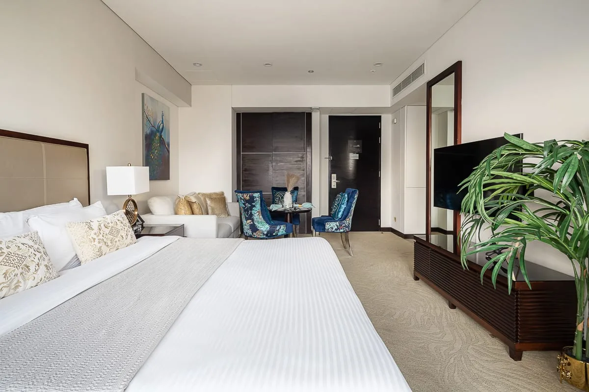 A bedroom with a large bed, seating area, and television.