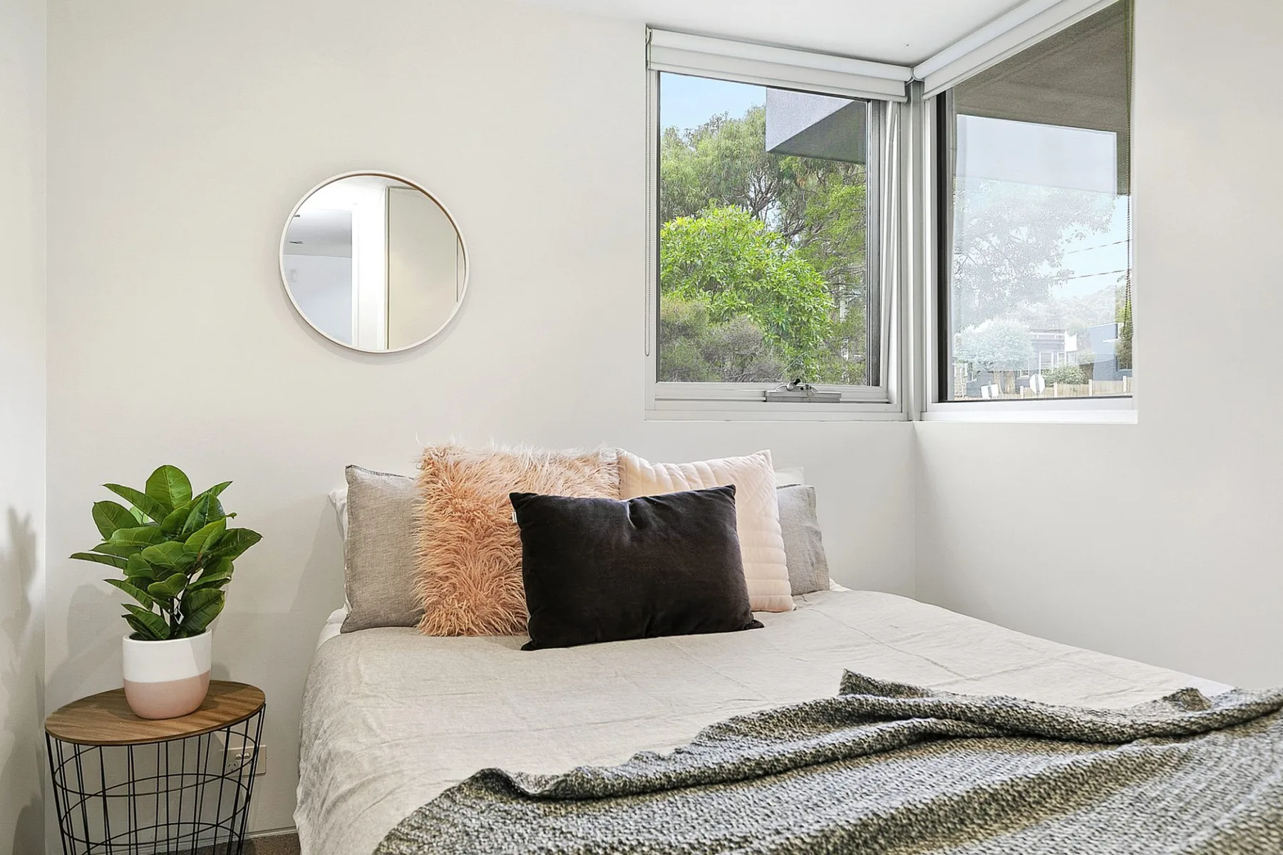 Un dormitorio luminoso con una cama junto a una ventana abierta.