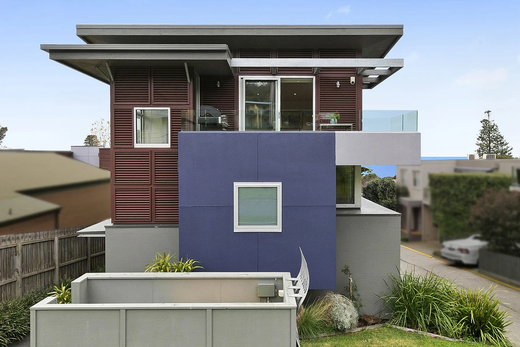 Casa moderna de varios niveles con una pared exterior azul y terraza en la azotea.