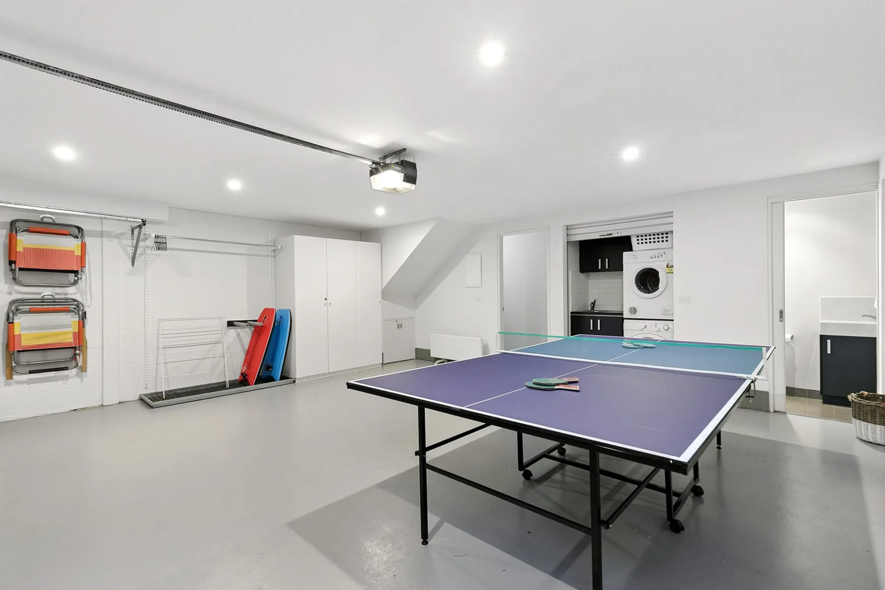 Una sala de recreación con una mesa de ping-pong y equipo plegado junto a la pared.