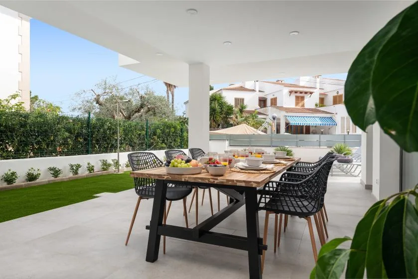 A covered outdoor dining area with a table and seating beside a garden.