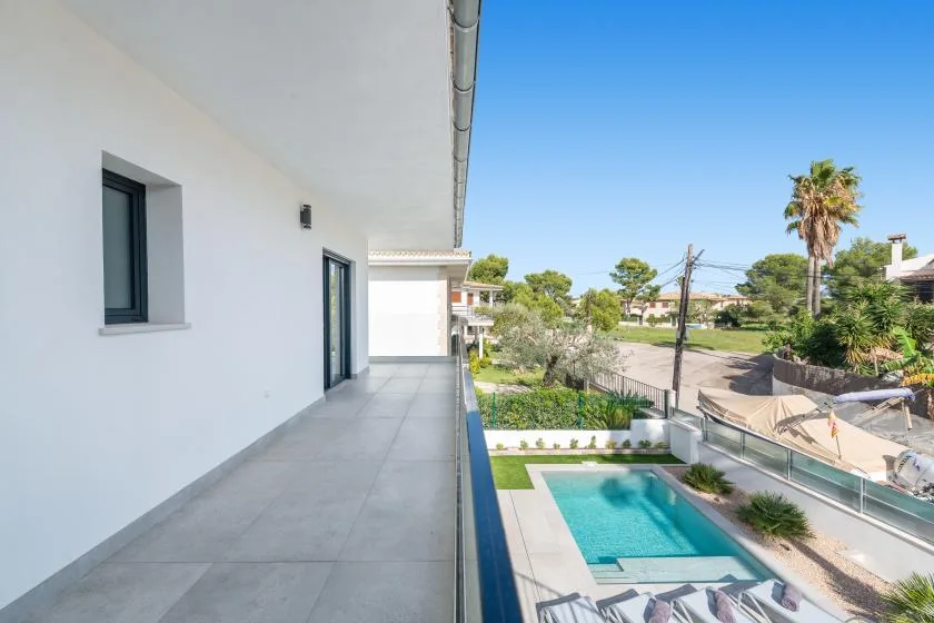 Un balcón da a una piscina y a una zona exterior ajardinada.