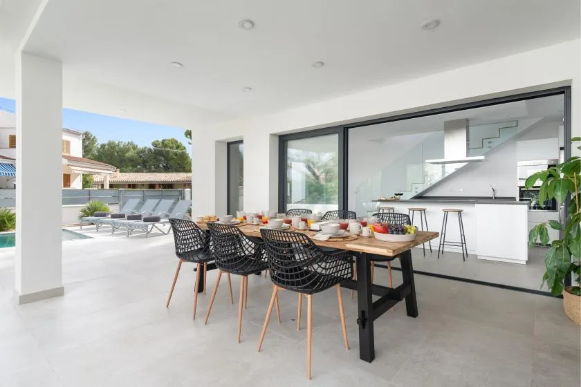 An outdoor dining area beside a modern kitchen, with a table and chairs.
