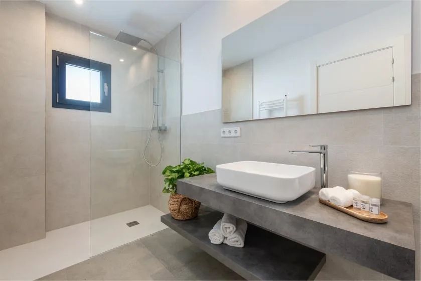 Un baño moderno con ducha, lavabo y un espejo grande.