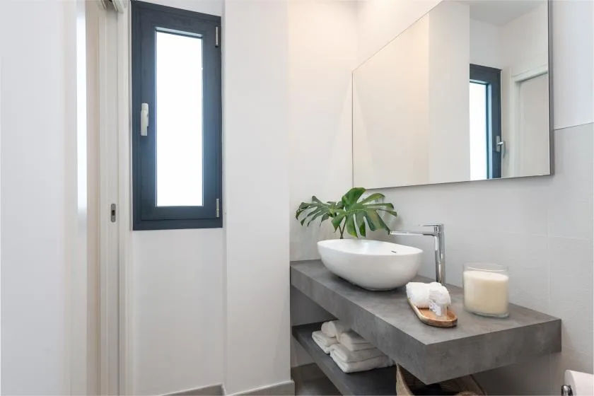 Un lavabo de baño moderno con un cuenco blanco bajo un espejo de pared.