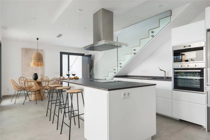 Una cocina y comedor de planta abierta con una isla central y una escalera.