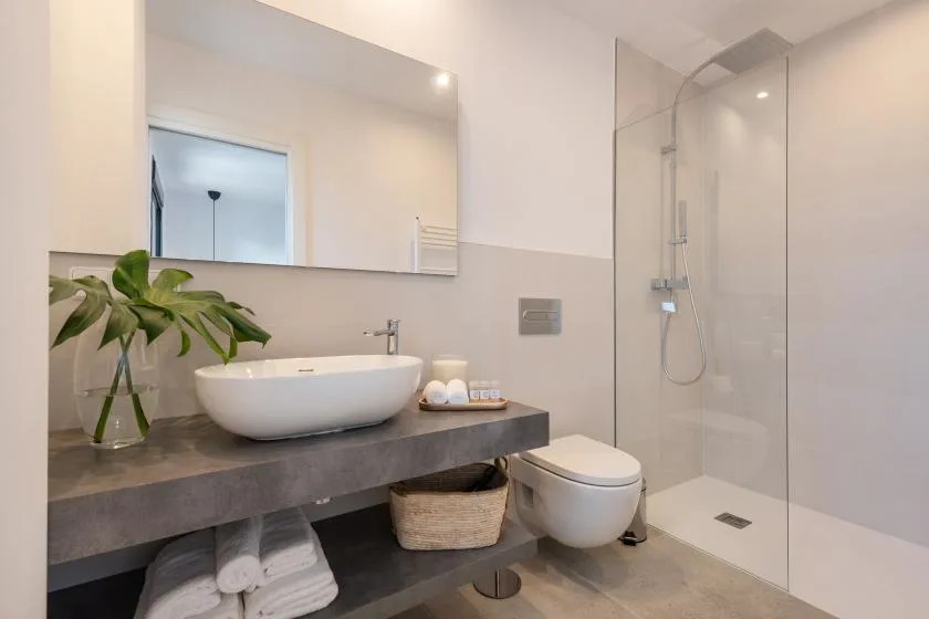 Un baño moderno con lavabo, inodoro y ducha de vidrio.