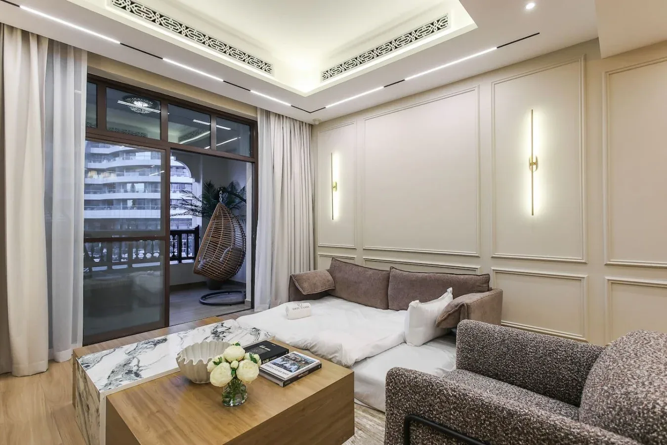 Una sala luminosa tiene una zona de asientos, una mesa de centro y ventanas al balcón.
