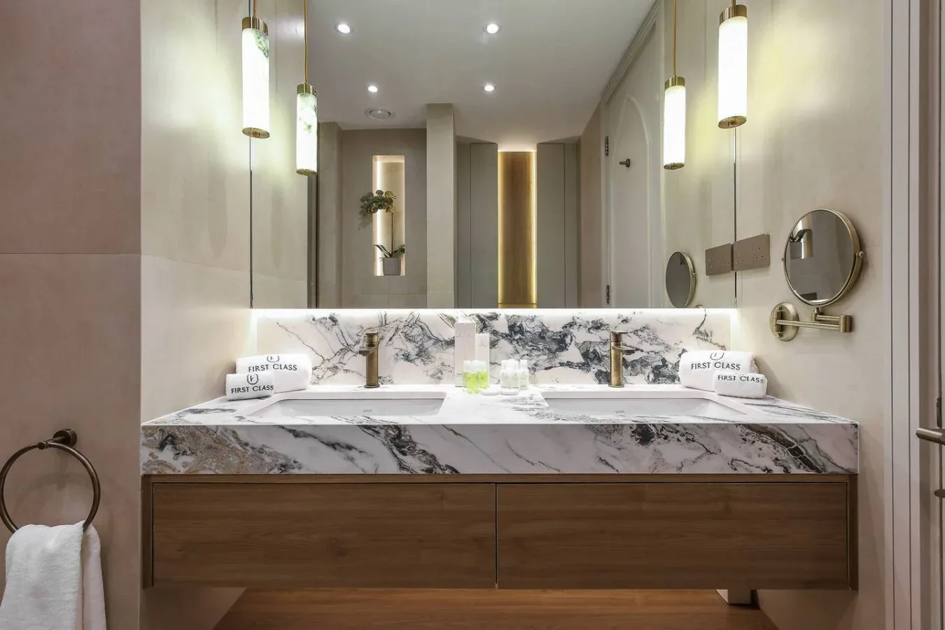 Un tocador de baño moderno con un espejo amplio y lámparas colgantes iluminadas.