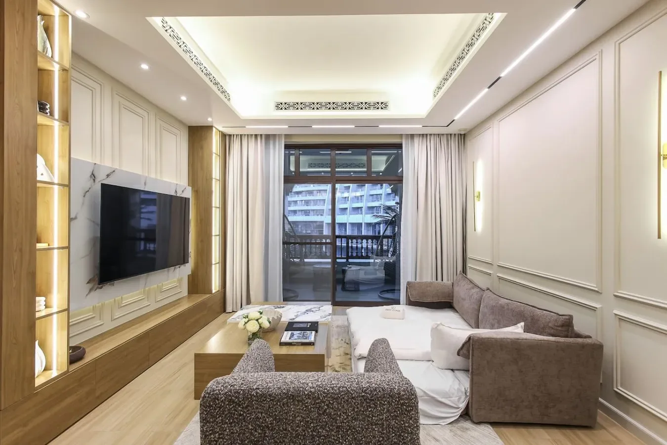 Una sala luminosa con asientos, un televisor y grandes ventanas.
