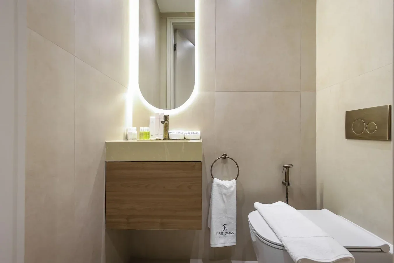 Un lavabo de baño con espejo iluminado y una toalla junto al inodoro.