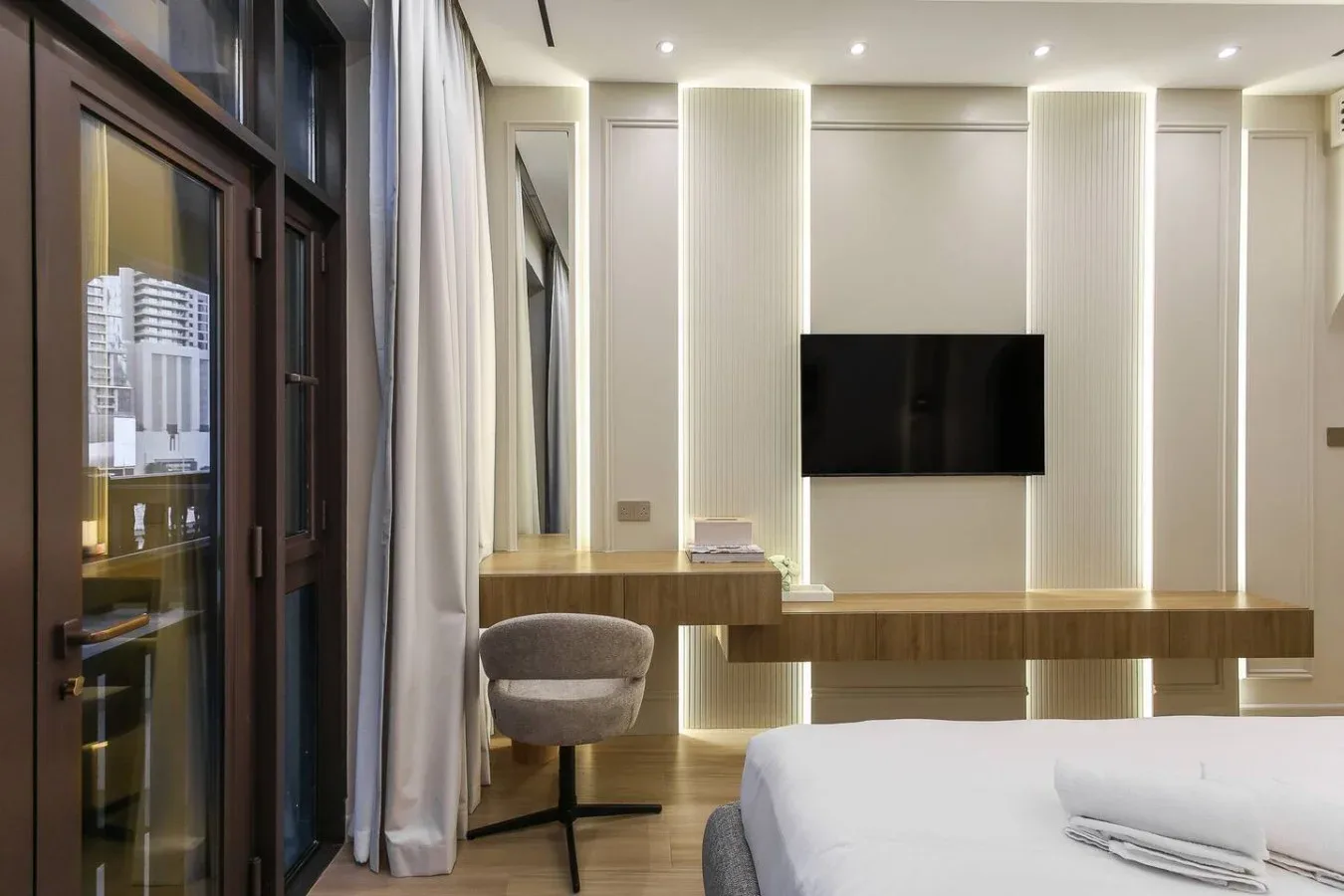 Un dormitorio con televisor de pared, escritorio y asiento.