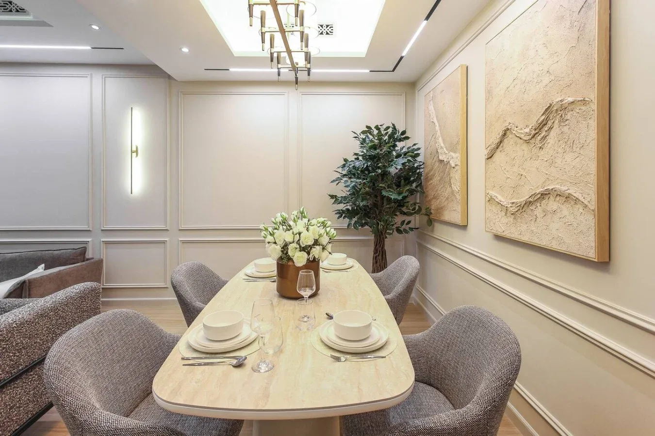 Un comedor con una mesa puesta, asientos tapizados y cuadros enmarcados.