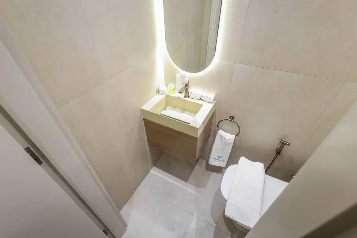 Un baño compacto con lavabo, espejo iluminado e inodoro.