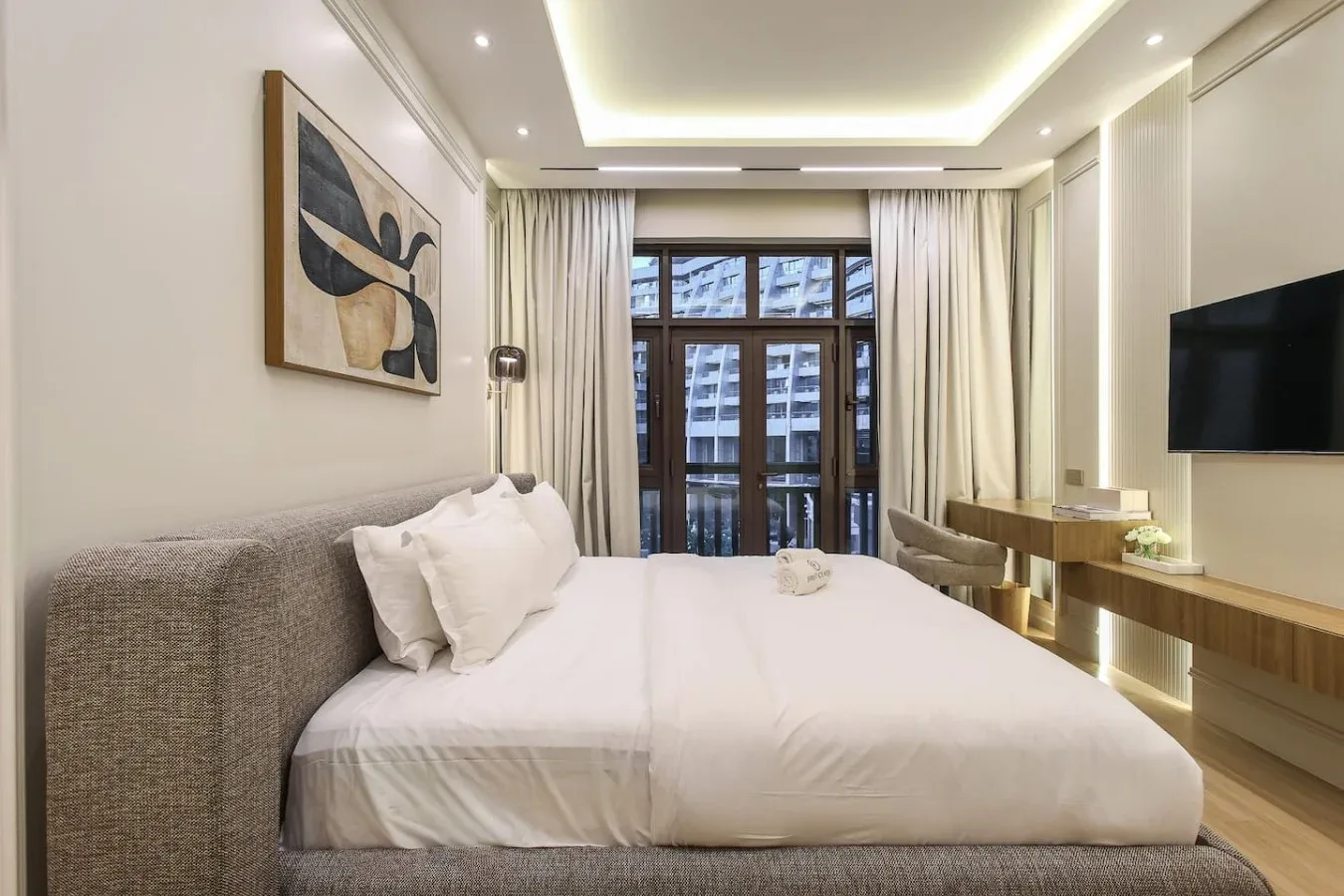 Un dormitorio con una cama grande, un cuadro enmarcado y un televisor montado en la pared.