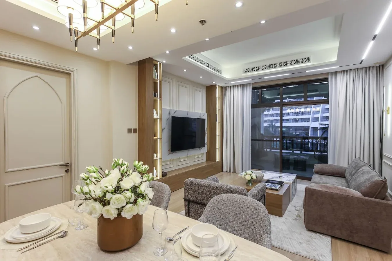 Una sala y comedor integrados tienen un televisor, asientos y una mesa preparada para comer.
