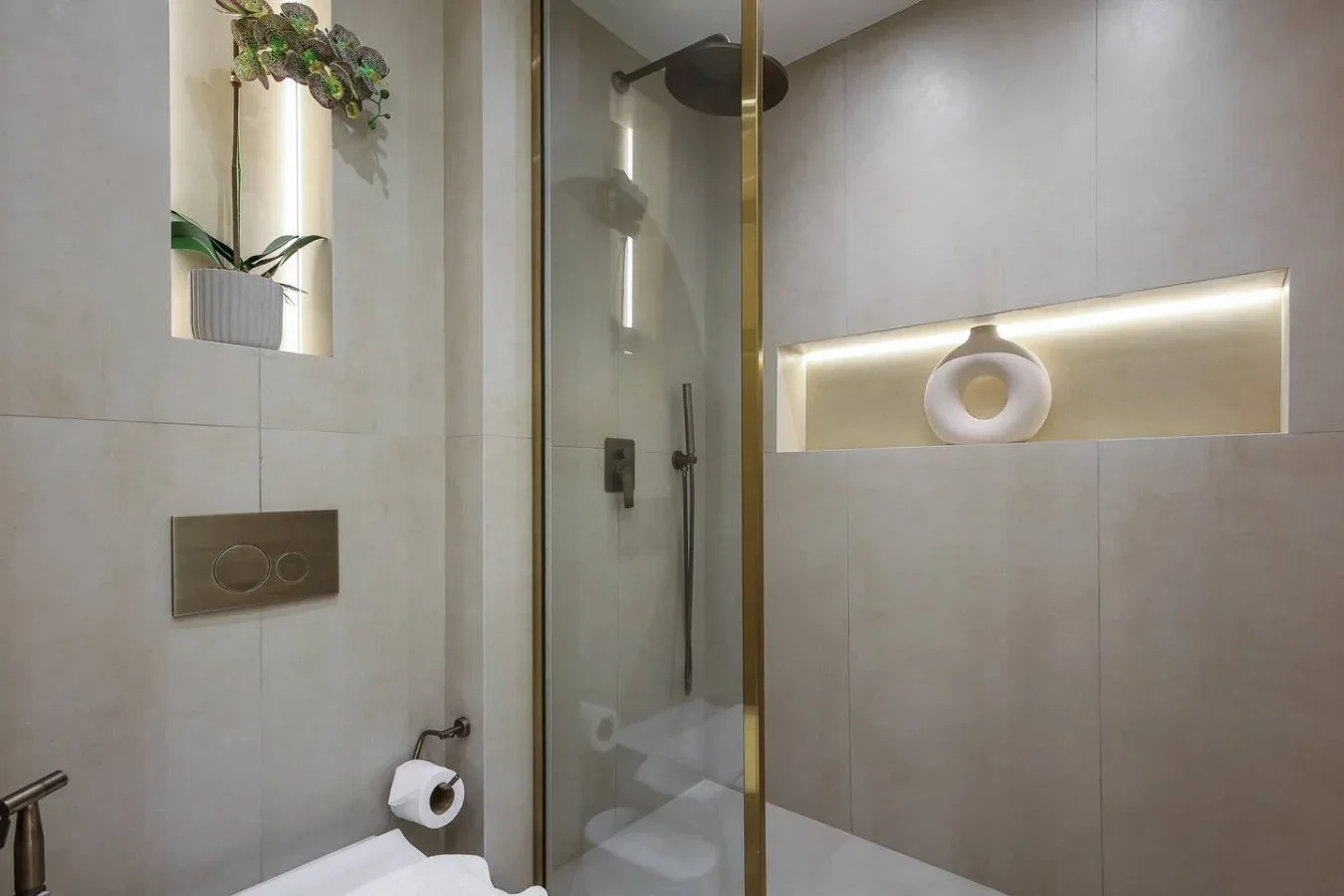 Un baño moderno con ducha de vidrio y un nicho iluminado.