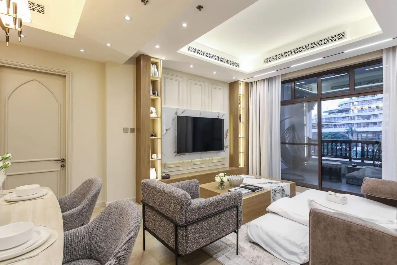 Una sala luminosa con asientos, un televisor y ventanales.