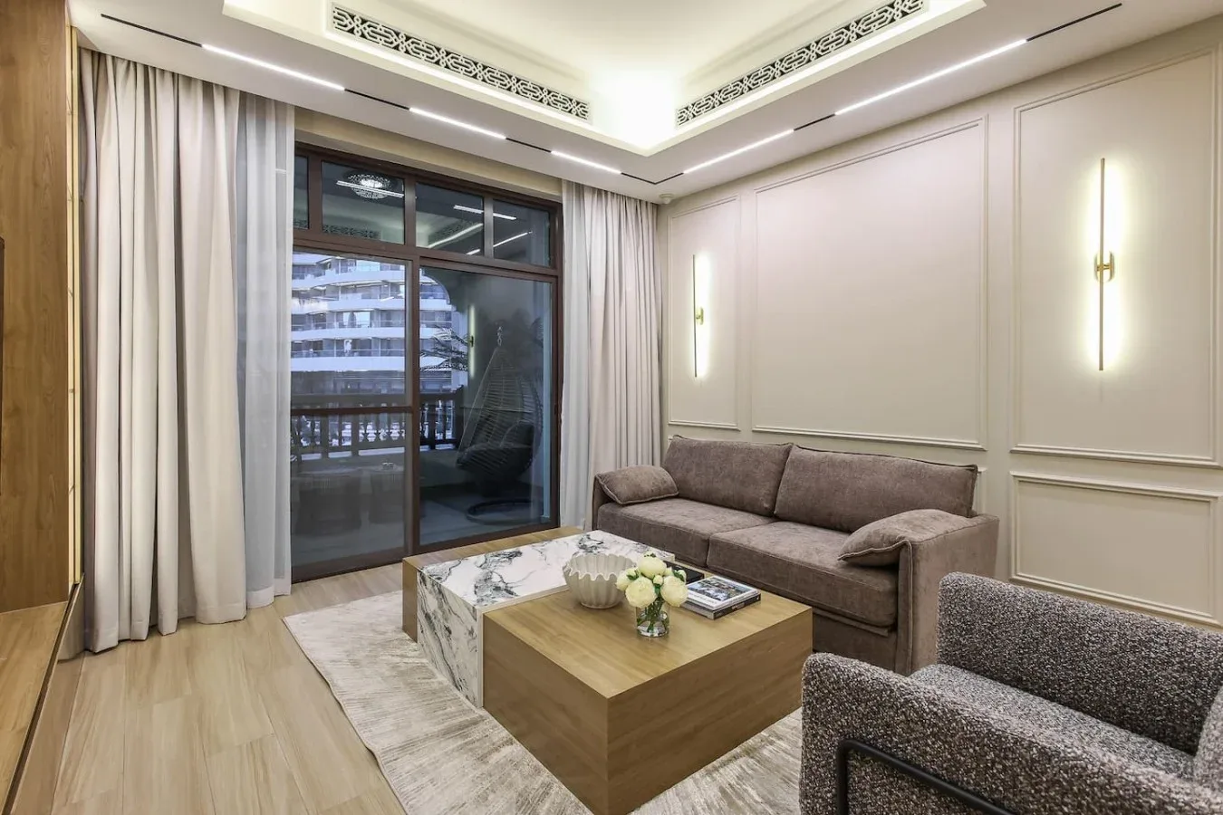 Una sala de estar con asientos alrededor de una mesa de centro junto a ventanas con cortinas.