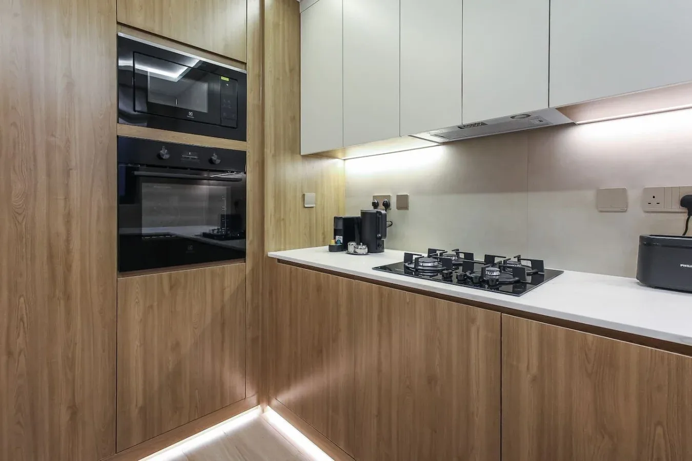 Una cocina moderna con gabinetes de madera, electrodomésticos empotrados y una placa de cocina.