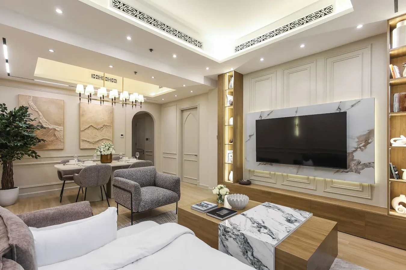 Una sala de estar con asientos, un televisor montado en la pared y una mesa de centro con vetas marmoleadas.