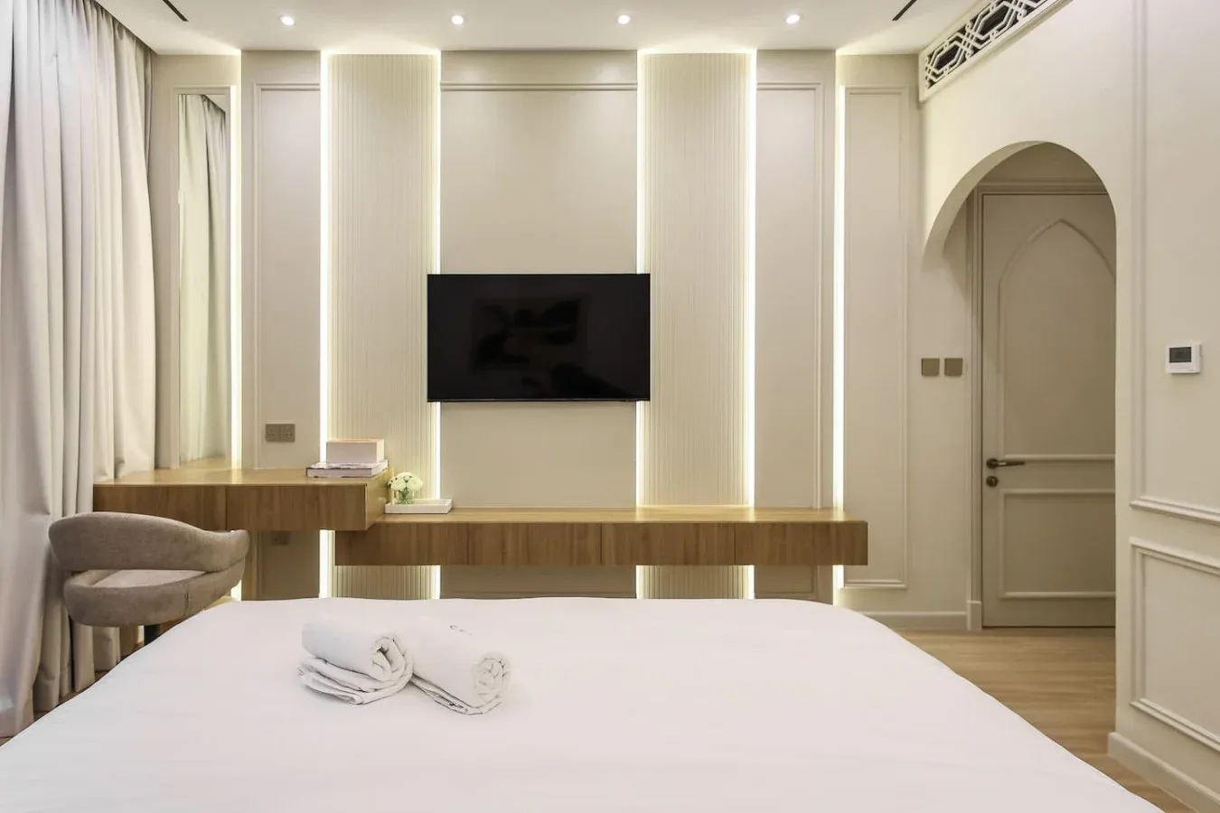 Un dormitorio con un televisor montado en la pared sobre una consola larga.