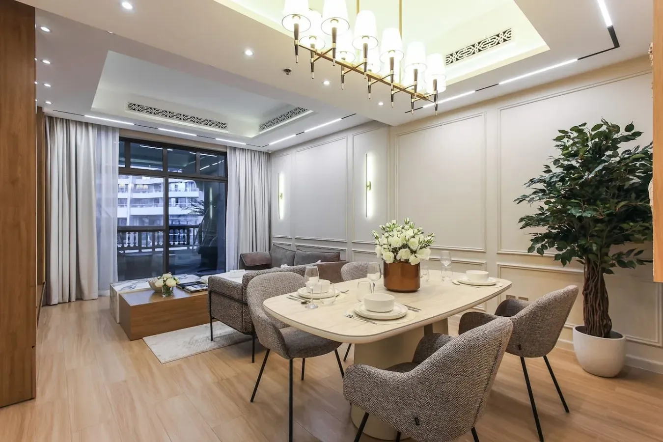 Un comedor luminoso con mesa, sillas y una zona de estar junto a grandes ventanas.