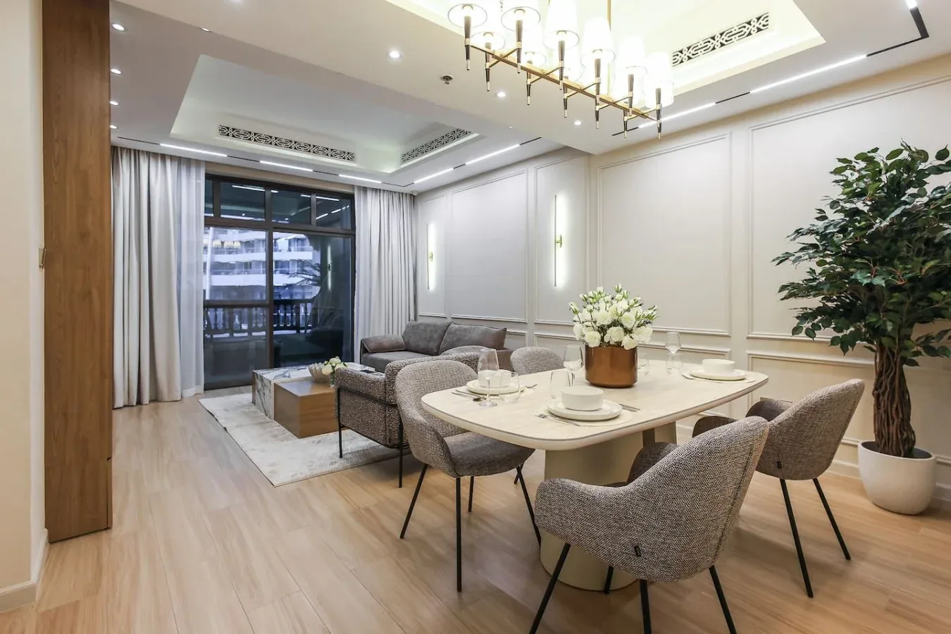 Un comedor luminoso con una mesa, asientos tapizados y grandes ventanas.